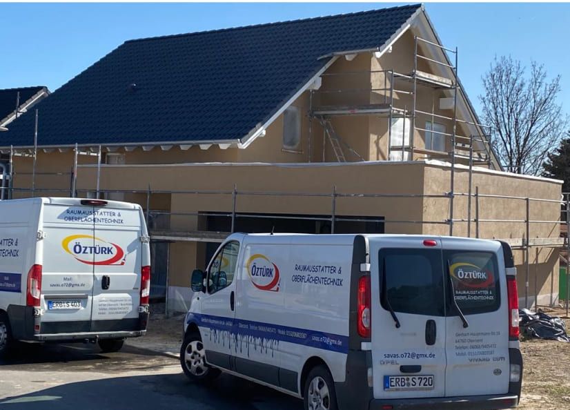 Firmenwagen vor einem Hausbau